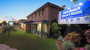A brick building with a covered patio and a sign for Park Beach Resort Motel. - Romantic King Spa Suite Perfect for Couples in Coffs Harbour (Coffs Harbour)