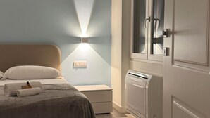 Ein Schlafzimmer mit einem Bett, einer Wandlampe, einem Fenster und einer Heizung.