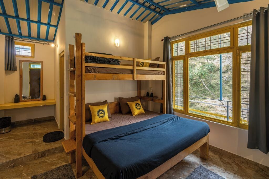A bunk bed room with a large window, wooden beams, and a mirror.