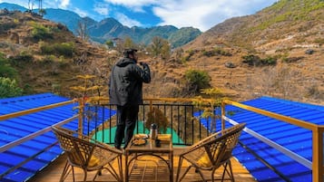 Un balcón con mesa y sillas, con vistas a un paisaje montañoso.