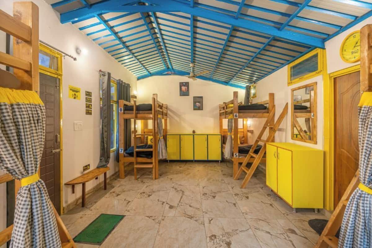 A room with bunk beds, a yellow cabinet, and a green mat on the floor.
