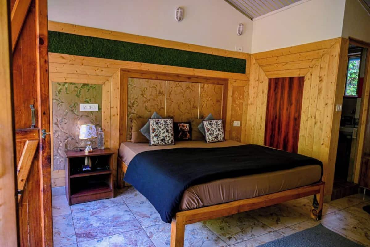 A wooden-framed bedroom with a bed, pillows, a nightstand, and a lamp.