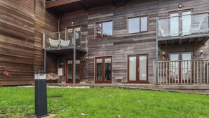 Ein zweistöckiges Holzhaus mit Balkon und Außenbestuhlung.