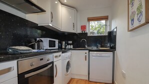 Eine kompakte Küche mit Mikrowelle, Backofen, Waschmaschine und Geschirrspüler.