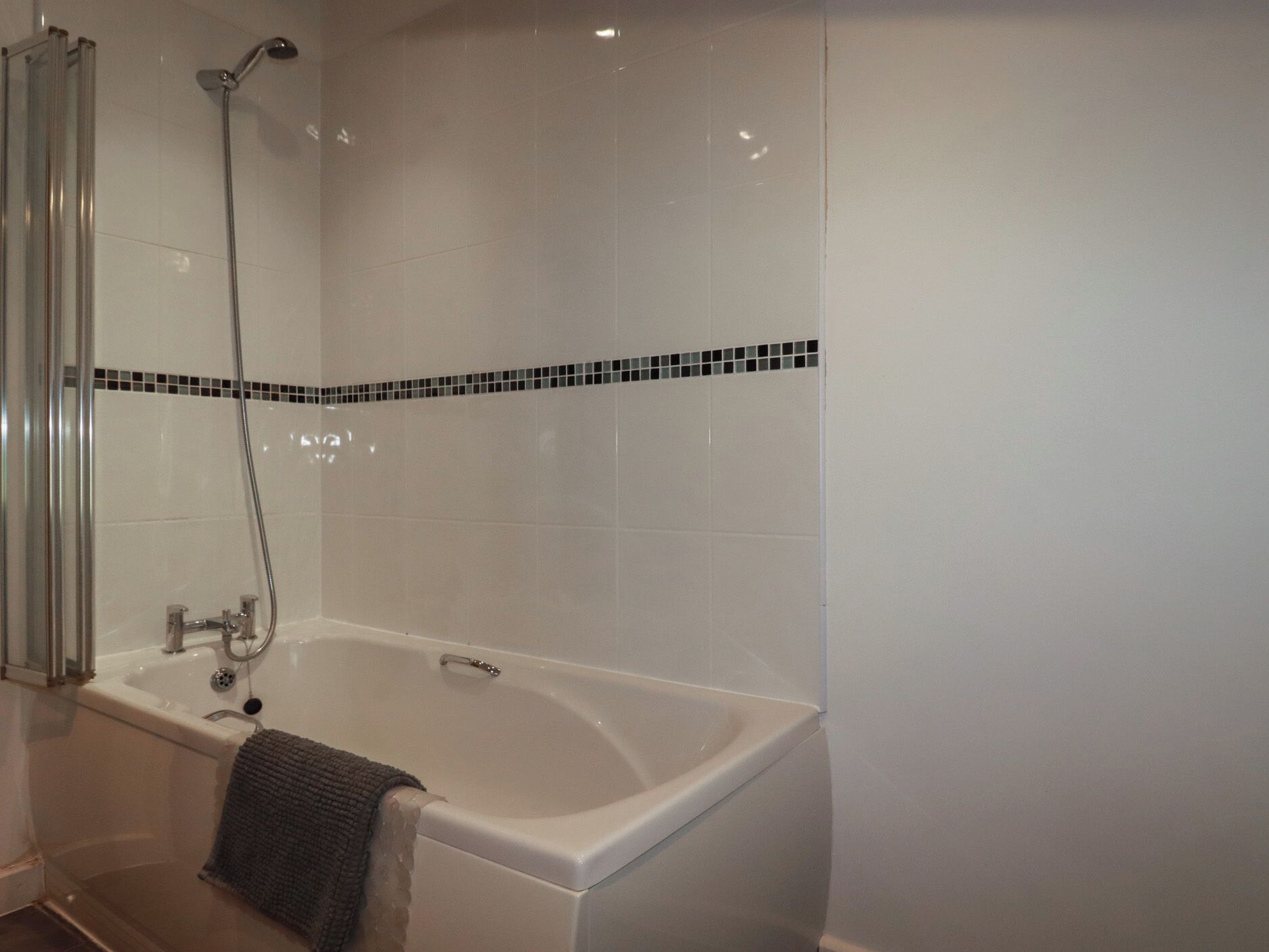 Une salle de bain moderne équipée d’une baignoire, d’une douche et d’un espace de douche séparé par des parois en verre.