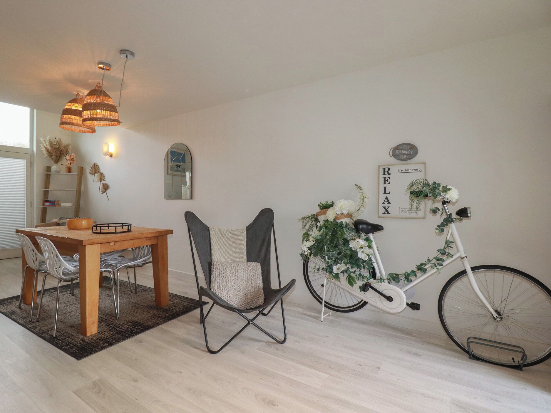 Un coin repas avec une table et des chaises en bois, un vélo et un panneau fixé au mur.