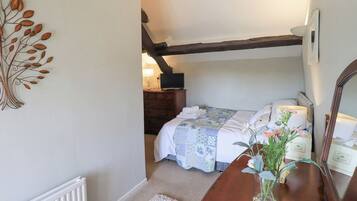 A bedroom with a bed, a dresser, a mirror, and a decorative metal wall piece.