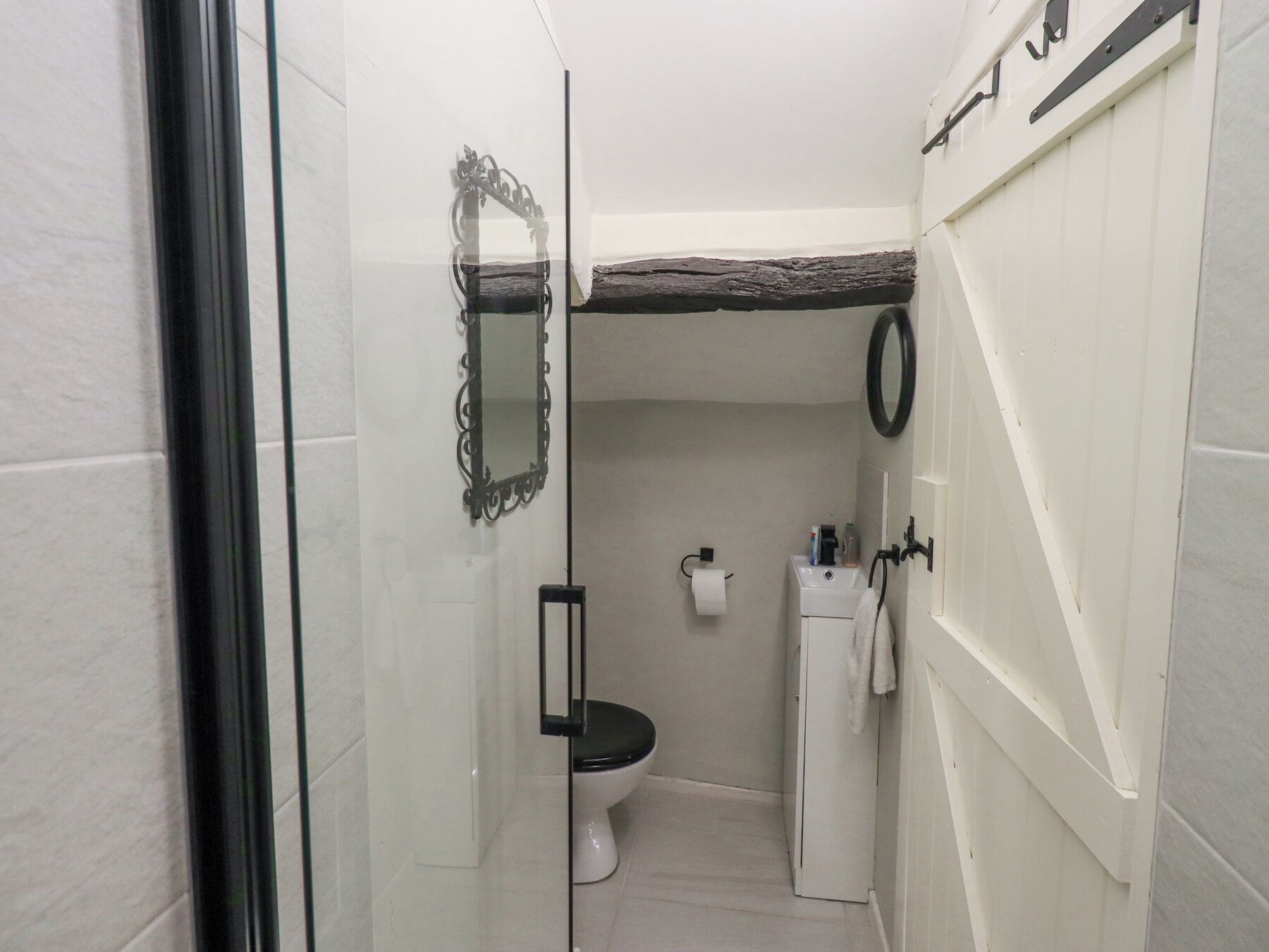 A narrow bathroom with a toilet, sink, and mirror.