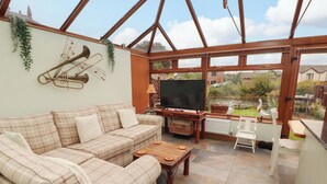 A cozy living room with a checkered sofa, a wooden coffee table, and a TV. - Beckside Cottage (Penrith)