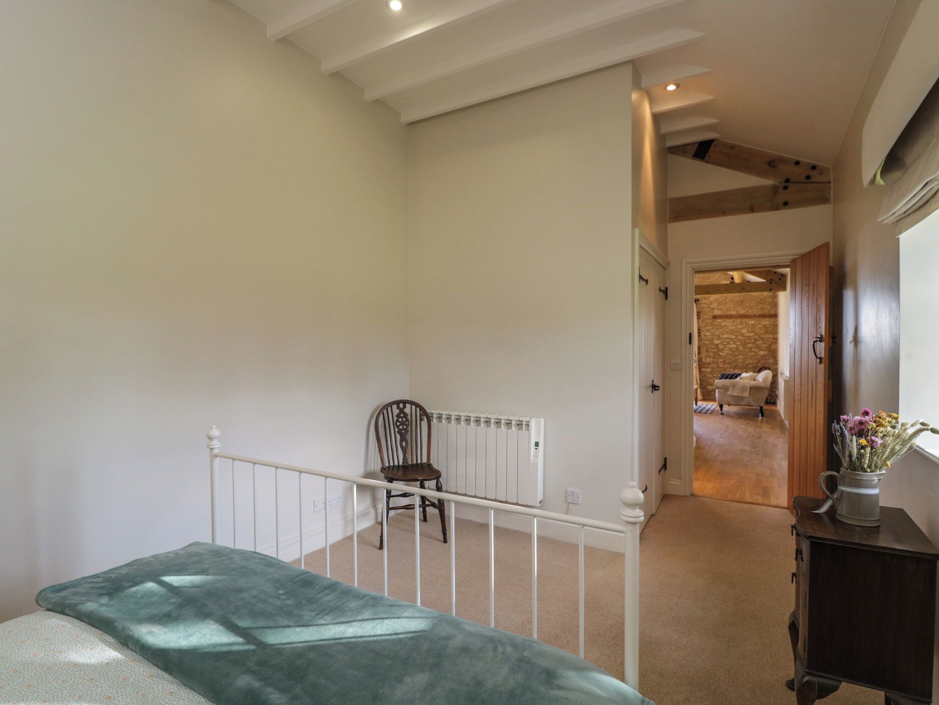 Una habitación amplia con techo alto, un radiador, una silla y una cama.