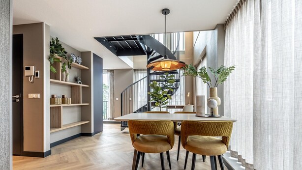 A modern dining area with a wooden table, two upholstered chairs, and a black pendant light.