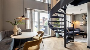 A modern living room with a spiral staircase, a round dining table, and a sofa.
