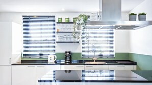 A modern kitchen with a central island, stainless steel appliances, and a window with blinds. - Waterfront Holiday Home with Terrace Views (Stavoren)