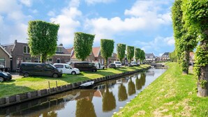 A canal lined with parked cars and houses with a narrow waterway. - Waterfront Holiday Home with Terrace Views (Stavoren)