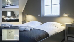 A modern bedroom with a large window, a bed with white linens, a desk with a lamp, and a mirror. - Waterfront Holiday Home with Terrace Views (Stavoren)