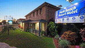 Un bâtiment en briques doté d’un patio couvert et d’une enseigne indiquant « Park Beach Resort Motel ».
