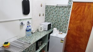 A compact kitchen with a sink, a microwave, a small refrigerator, and a tiled backsplash.