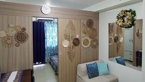 A living room with a sofa, a dining table, and a clock on the wall.
