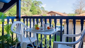 A balcony with a table and chairs, overlooking a residential area with houses and greenery. - Bosquet des Ecureuils 17 by Interhome (Capbreton)
