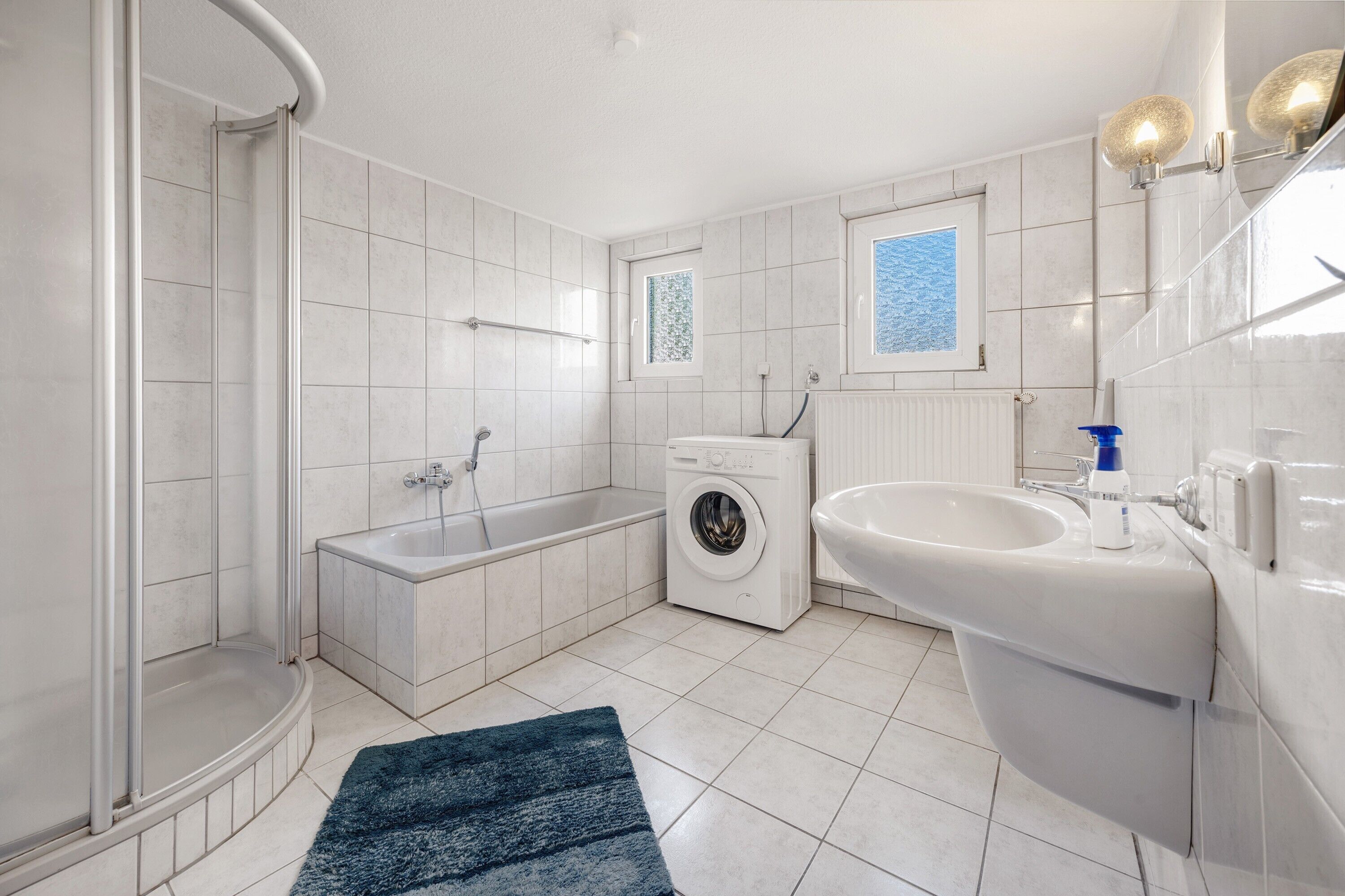 Ein modernes Badezimmer mit Dusche, Badewanne, Waschmaschine und Waschbecken.