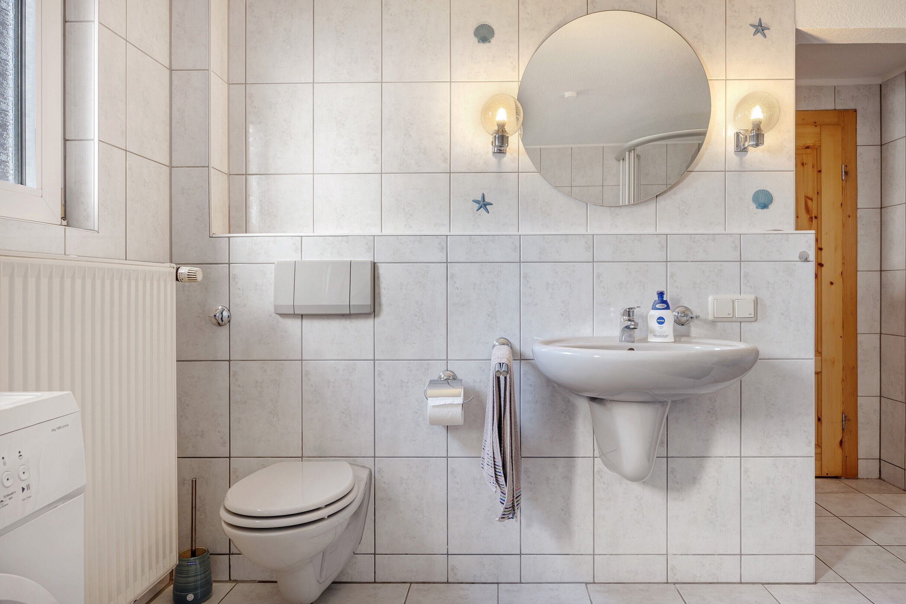 A bathroom with a toilet, sink, mirror, and towel rack.