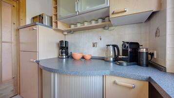 Eine Küche mit integriertem Mikrowellenherd, Kaffeemaschine und Wasserkocher auf der Arbeitsfläche.
