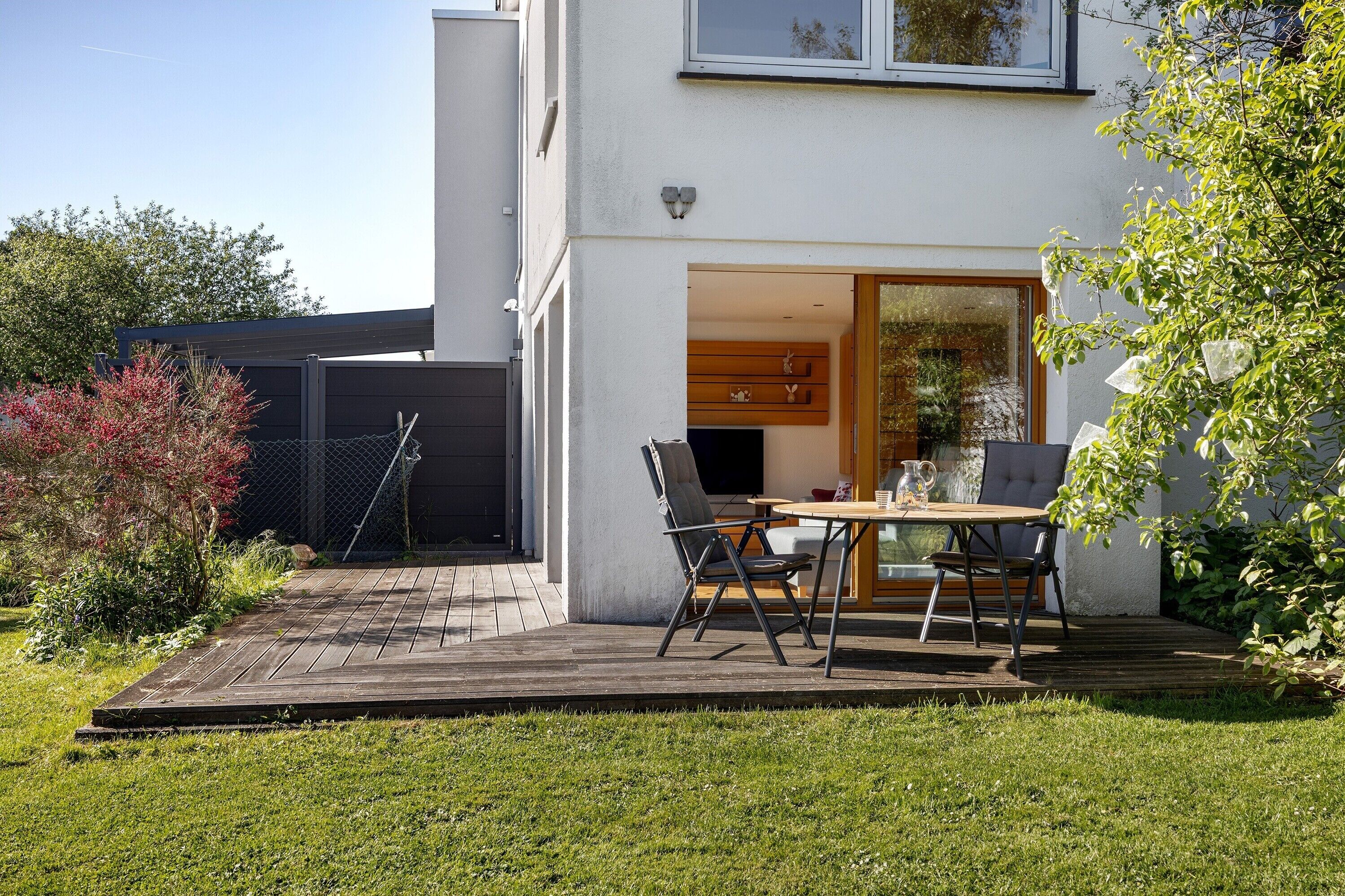 Ein modernes Haus mit Terrasse, einem Esstisch und Stühlen.