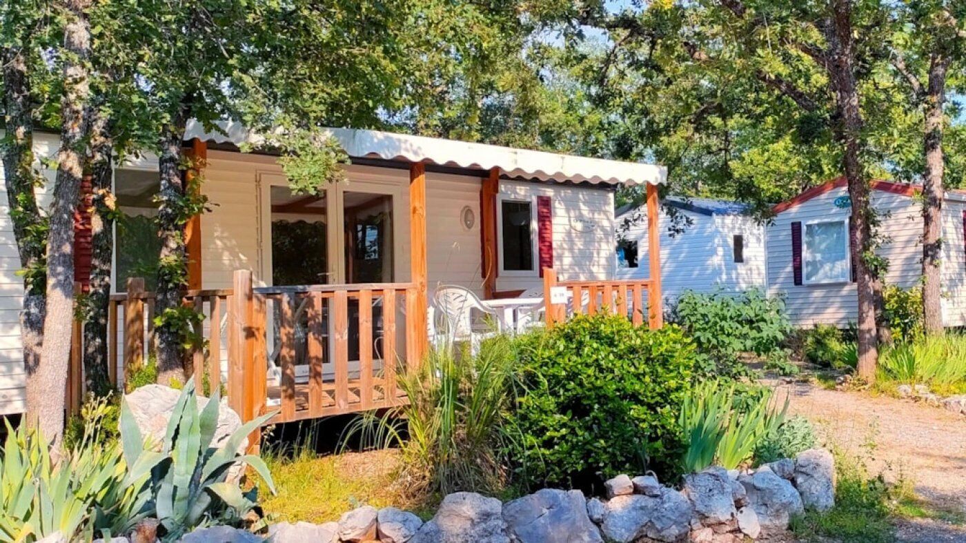A mobile home with a porch and a small garden area.