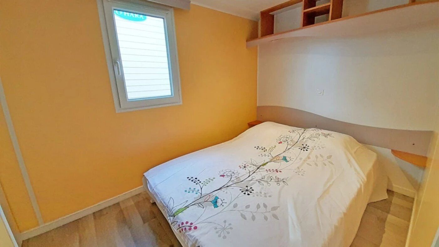 A bedroom with a bed, a window, and a built-in shelf.