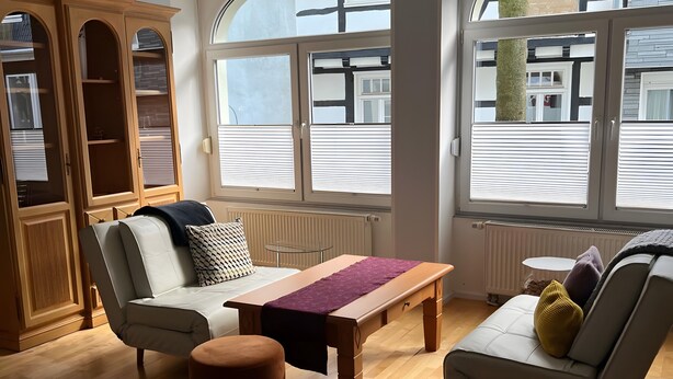 A modern living room with a sofa, ottoman, and a wooden coffee table. - Apartment 'Nr 1' with Wi-Fi (Schwelm)