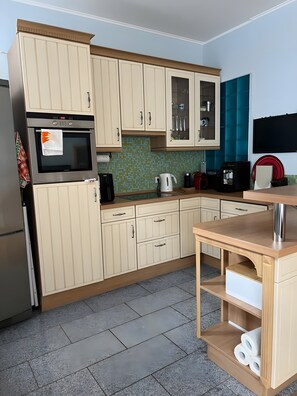 A kitchen with a microwave, oven, and cabinets. There is a coffee maker, toaster, and a sink.