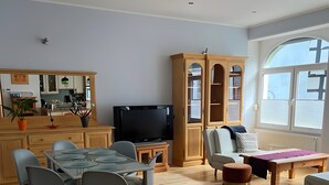 A modern living room with a dining area, a TV, and a large window. - Apartment 'Nr 1' with Wi-Fi (Schwelm)