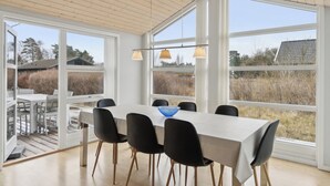 Un espace repas comprenant une table, des chaises et une vue dégagée grâce à de grandes fenêtres.