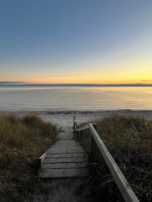 Un sendero de madera que lleva a una playa, con vista al océano.
