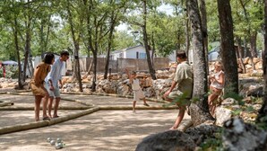 Un groupe de personnes jouant à la pétanque dans un cadre extérieur, avec des arbres et des rochers.
