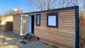 A small, single-room mobile home with a sliding door, a small porch, and a satellite dish. - ZEcamping 3* dog friendly mobil-home TV clim 29m2 5 pers (Bauduen)