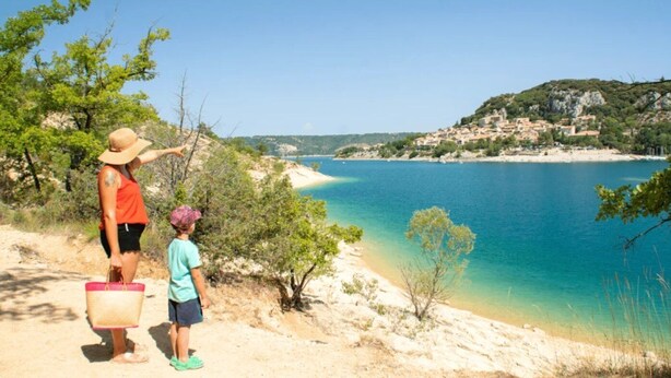 A coastal scene with a sandy path leading to a beach, overlooking a calm sea and a hillside settlement. - ZEcamping 3* dog friendly mobil-home TV clim 29m2 5 pers (Bauduen)