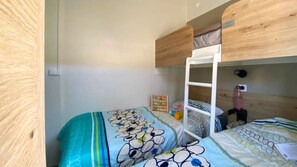 Une chambre avec un lit superposé, une échelle, une petite table et une étagère fixée au mur.