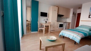 A compact living space with a kitchenette, a dining area, and a bedroom.