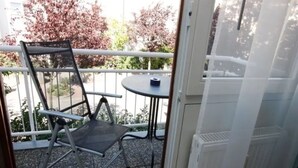 A balcony with a chair, a small table, and a door.