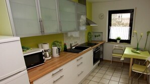 Cocina compacta con microondas, hervidor y lavabo.