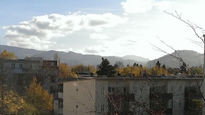 A multi-story building with a flat roof, surrounded by trees with autumn foliage, and mountains in the background. - Studio 'Falk Wohnung Nr -3-' with Mountain View, Balcony and Wi-Fi (Freiburg im Breisgau)
