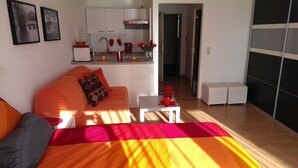 A modern apartment with a bed, orange sofa, kitchenette, and a view of the hallway. - Studio 'Falk Wohnung Nr -3-' with Mountain View, Balcony and Wi-Fi (Freiburg im Breisgau)