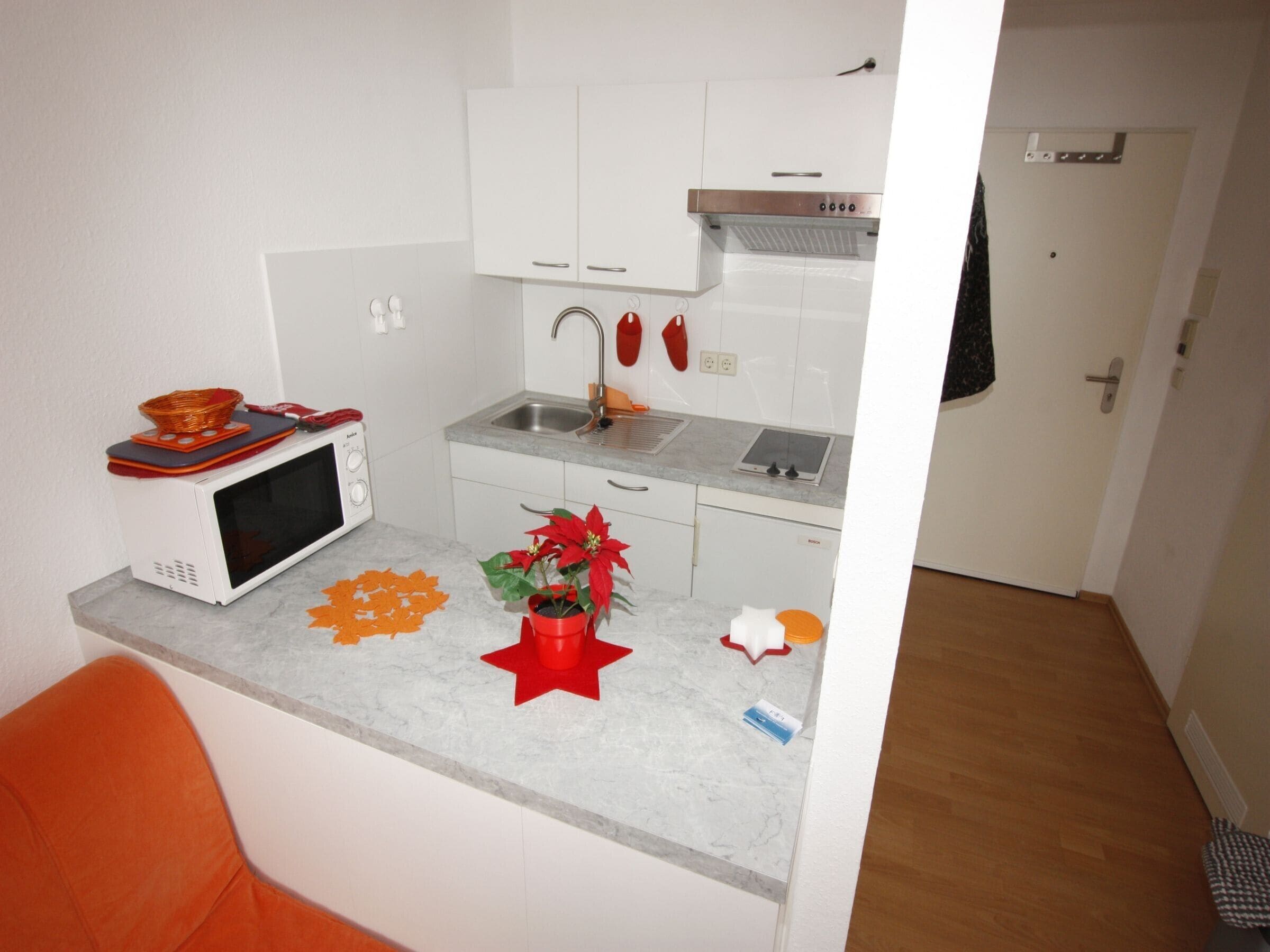 A compact kitchen with a microwave, sink, and cabinets.