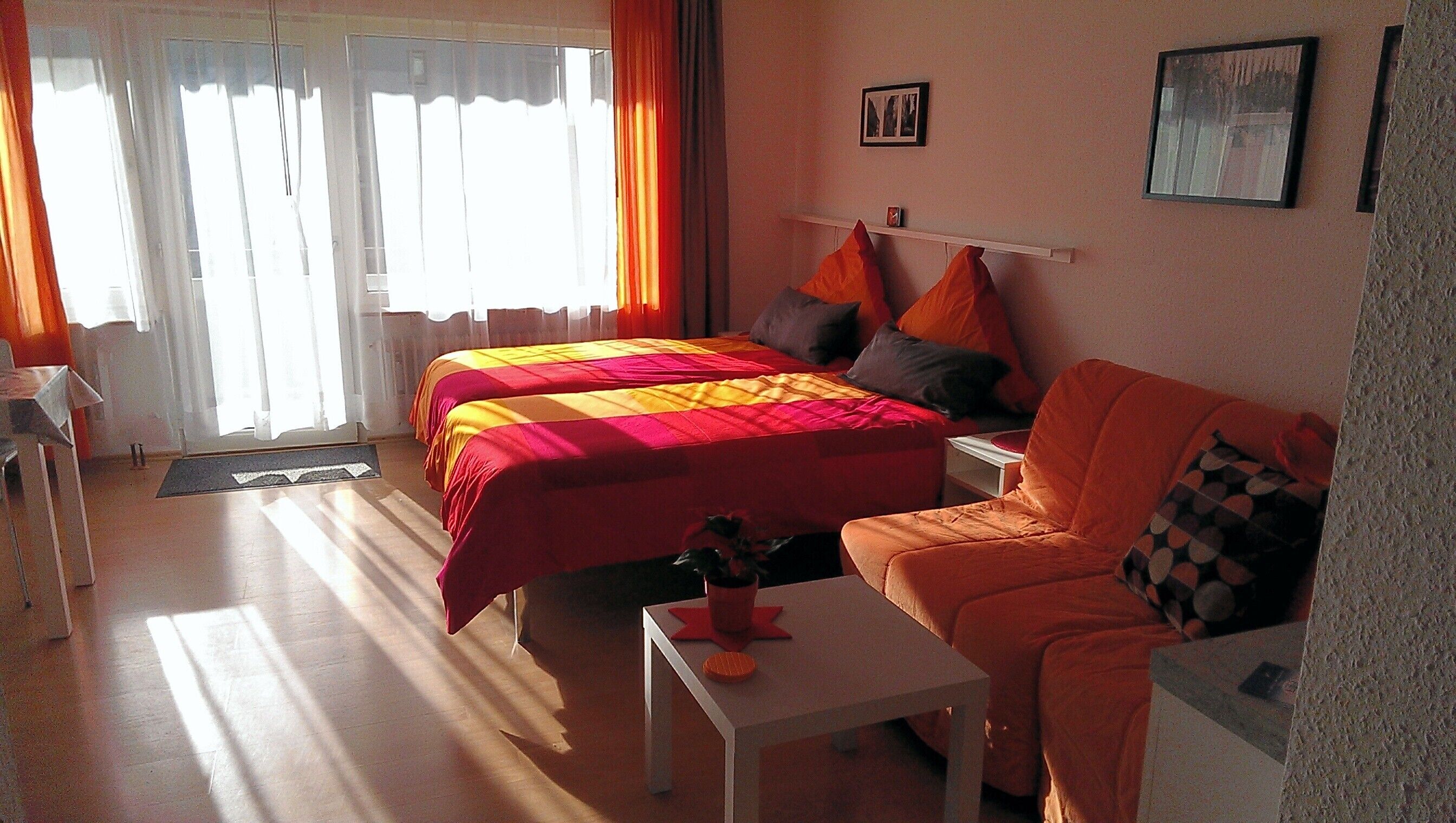 A room with two beds, a sofa, a small table, and a window with curtains.