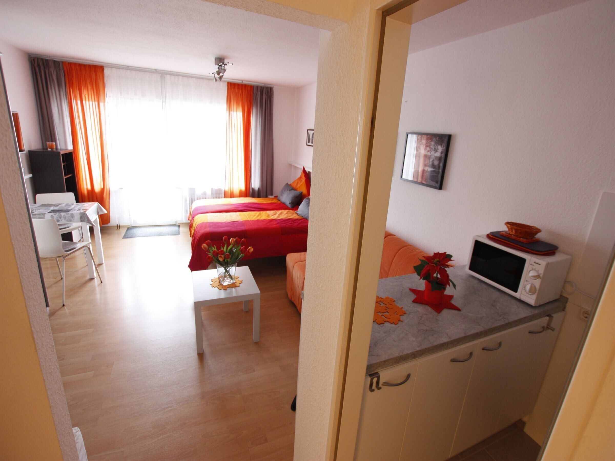 Ein Hotelzimmer mit einem Bett, einem Schreibtisch, einem Stuhl, einer Mikrowelle und einem kleinen Tisch mit einer Vase.