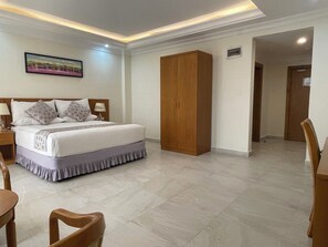 Un dormitorio con cama, armario de madera y zona de comedor con sillas.