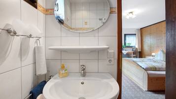 A bathroom with a sink, mirror, towel rack, and toilet paper holder.