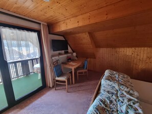 Ein gemütliches Dachzimmer mit einem Bett, einem Schreibtisch und einem Stuhl.