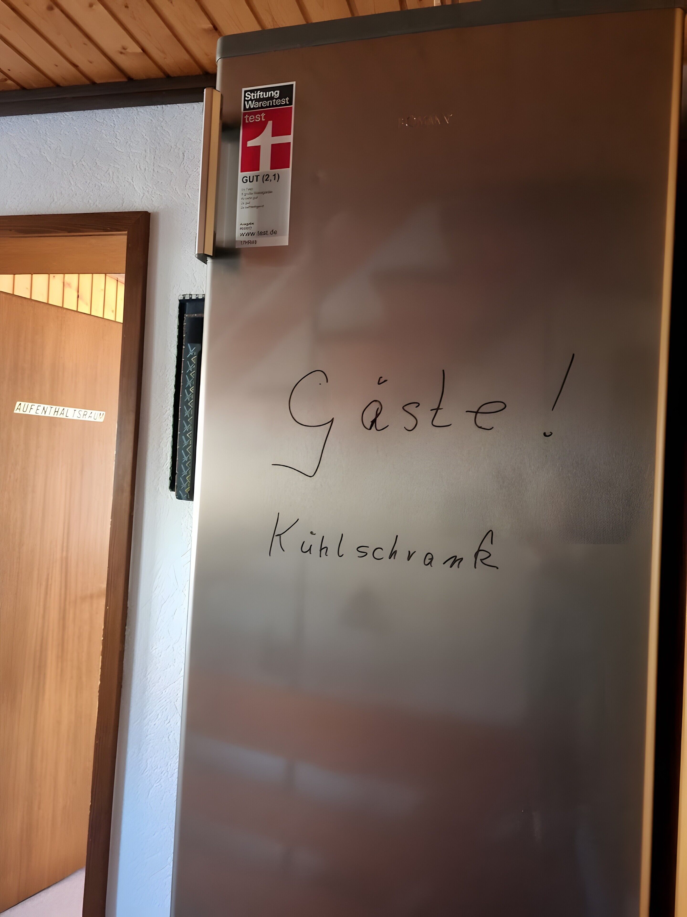 Een koelkast met een sticker en handgeschreven tekst.
